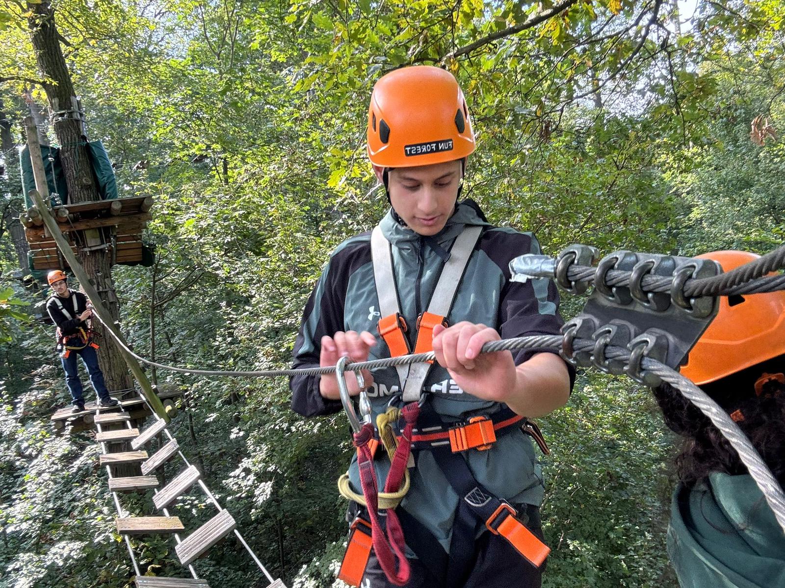 Schüler sichert sich am Karabiner im Hochseilgarten